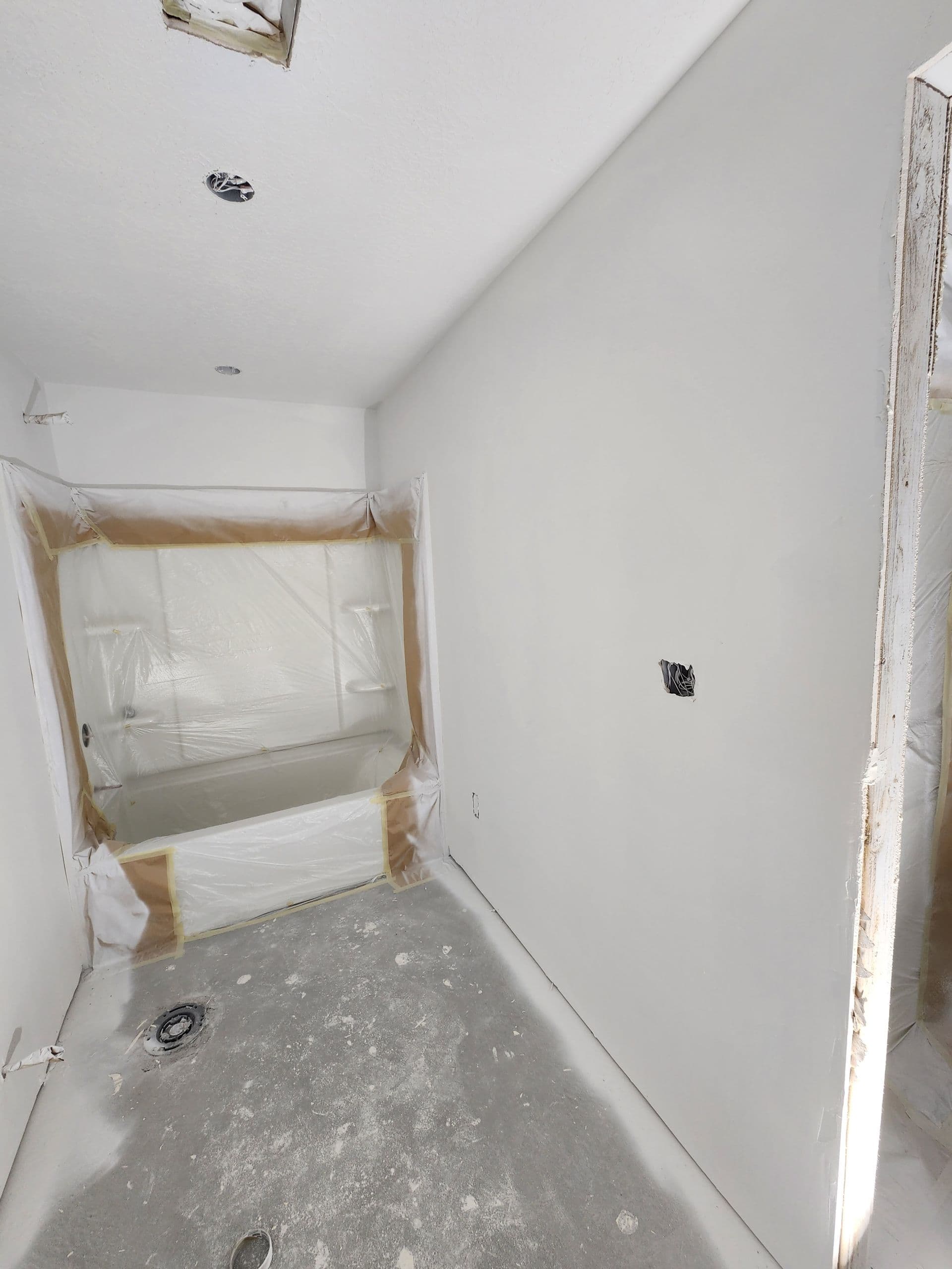 New-construction bathroom masked and primed, ready for a clean interior paint finish.